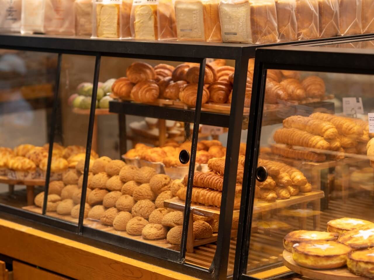 Bakery display case filled with fresh bread, croissants, and pastries for a bakery using Nommy online menus