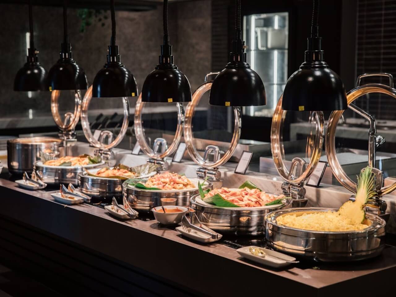 Buffet line with chafing dishes of hot food under black heat lamps