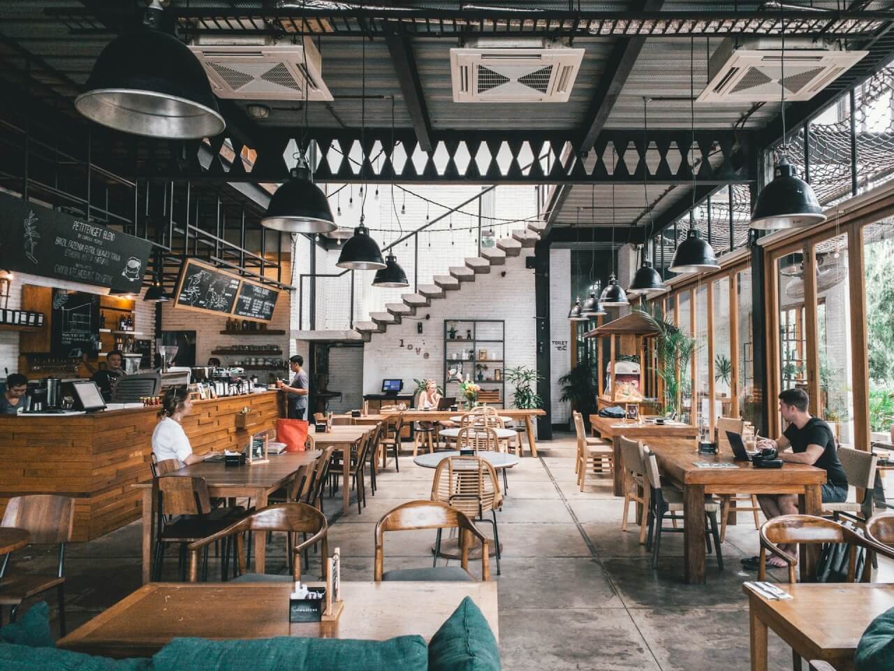Bright cafe interior with wooden tables, pendant lighting, and a service counter