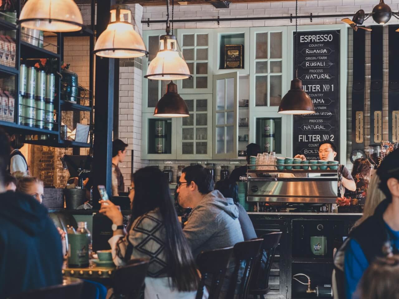 Coffee shop interior with customers seated beside an espresso bar and menu boards
