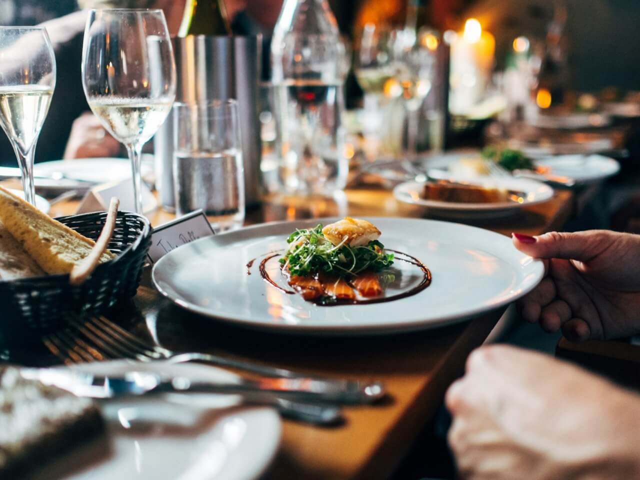 Fine dining restaurant table with a plated course, wine glasses, and candlelight
