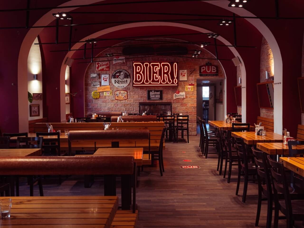 Gastropub dining room with arched ceilings, wooden tables, and a glowing beer sign