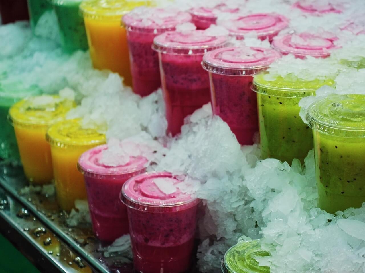 Rows of green, yellow, and magenta juice cups chilling on crushed ice