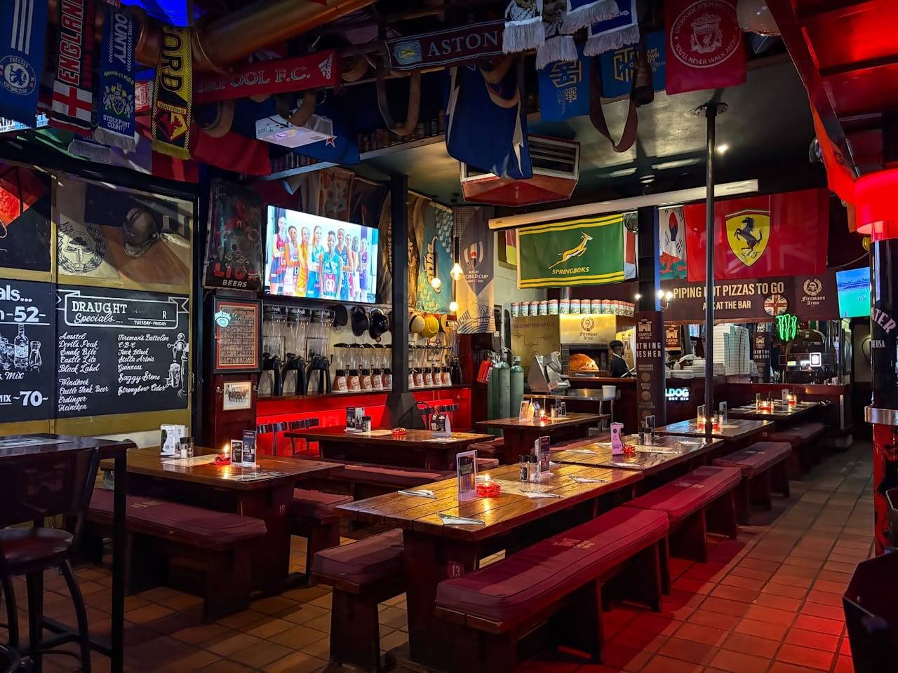 Sports bar interior with long tables, TV screens, football scarves, and team flags