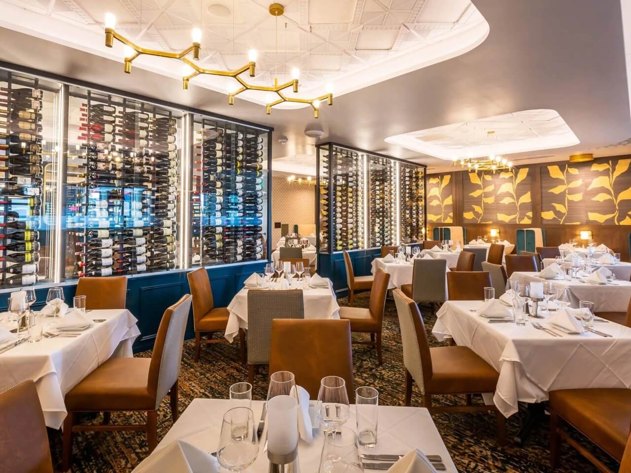 Steakhouse dining room with white tablecloth tables and floor-to-ceiling wine displays