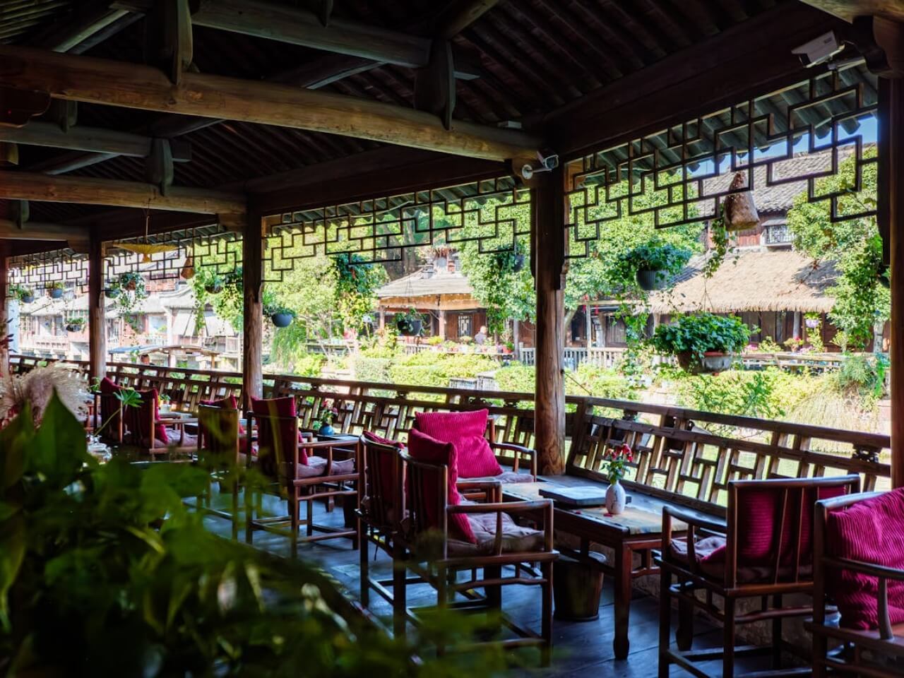 Open-air tea house terrace with wooden seating, hanging plants, and a garden courtyard view